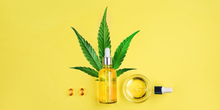 Bottle with CBD oil, pipette, capsules and cannabis leaf on a yellow background. Minimalism, flat lay.